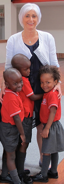 Three children give Jill a hug during her visit to their class in South Africa